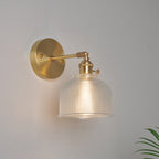 Lámpara de pared industrial de un luz con brazo oscilante de acabado en latón, pantalla de vidrio transparente